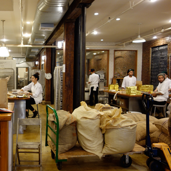 Behind the tasting room at Mast Brothers: sacks of cacao beans and staff wrapping chocolate bars.