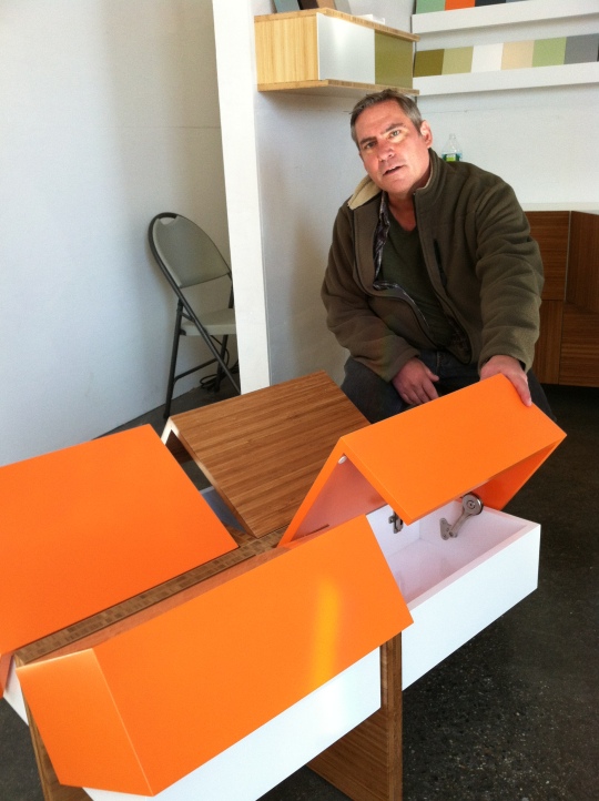 David Gotl lifts the four cubby covers of the streamlined coffee table,